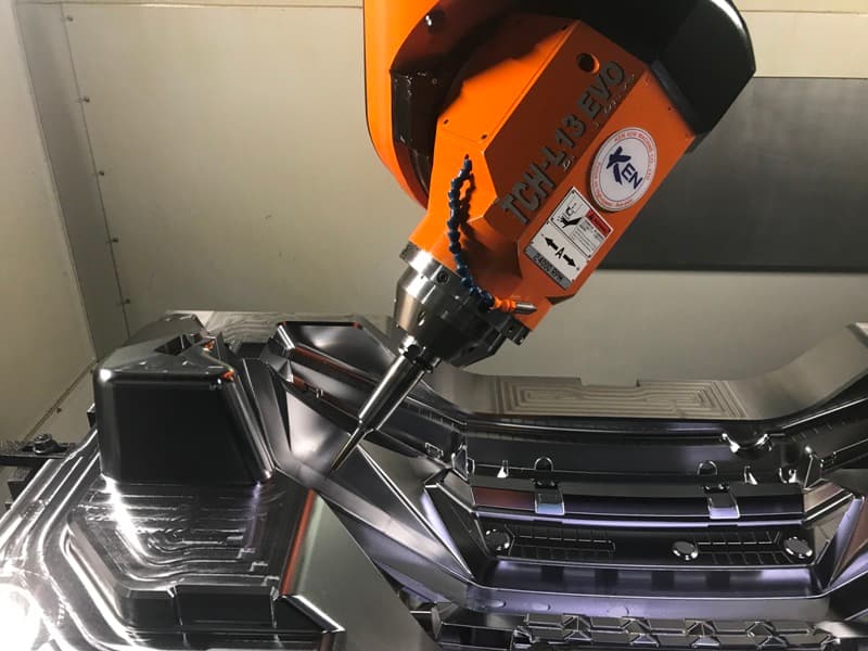 Five-axis machining head cutting a polished mold cavity